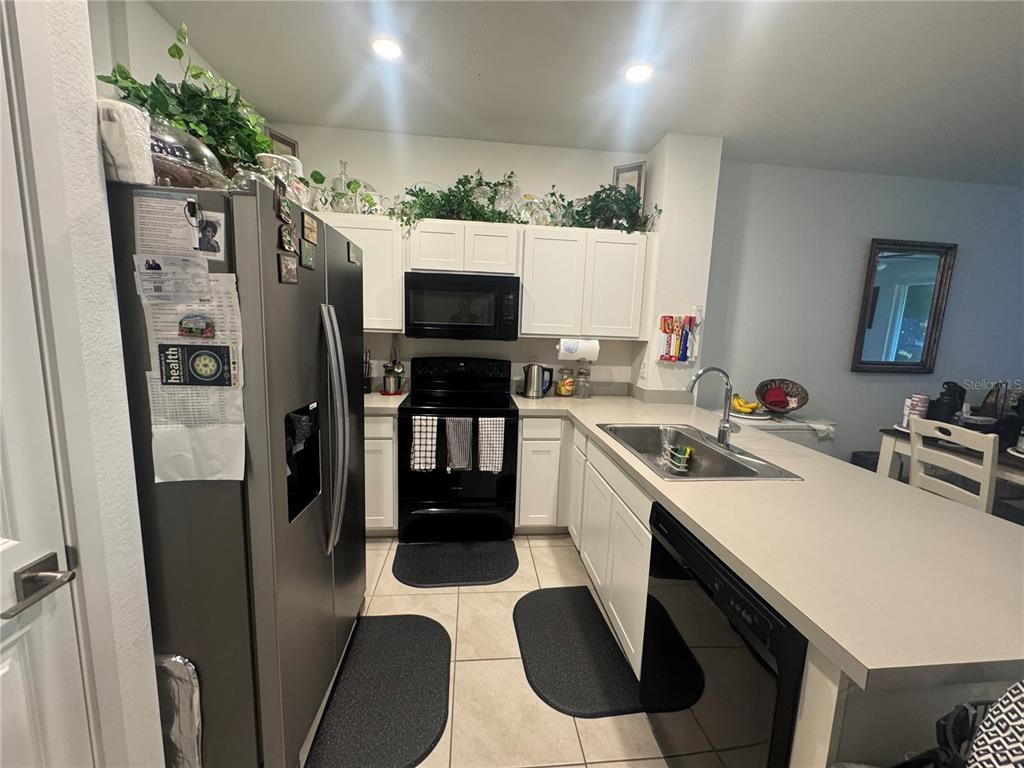 A kitchen features white cabinets, black appliances, a stainless steel sink, and tile flooring — 176 BANDOL STREET, WEST PALM BEACH, FL