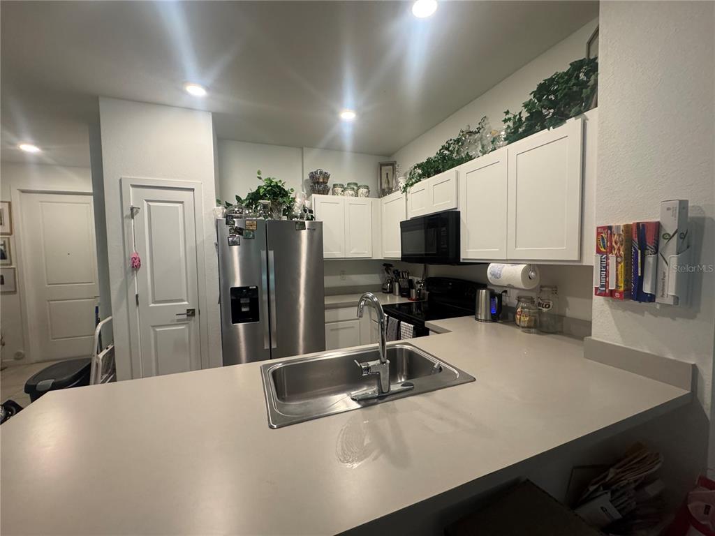 A kitchen features white cabinets, stainless steel appliances, and a sink on a peninsula countertop — 176 BANDOL STREET, WEST PALM BEACH, FL