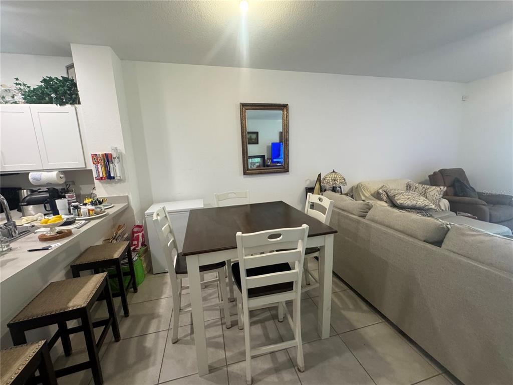 A dining area with a dark wood table and white chairs sits beside a kitchen counter — 176 BANDOL STREET, WEST PALM BEACH, FL