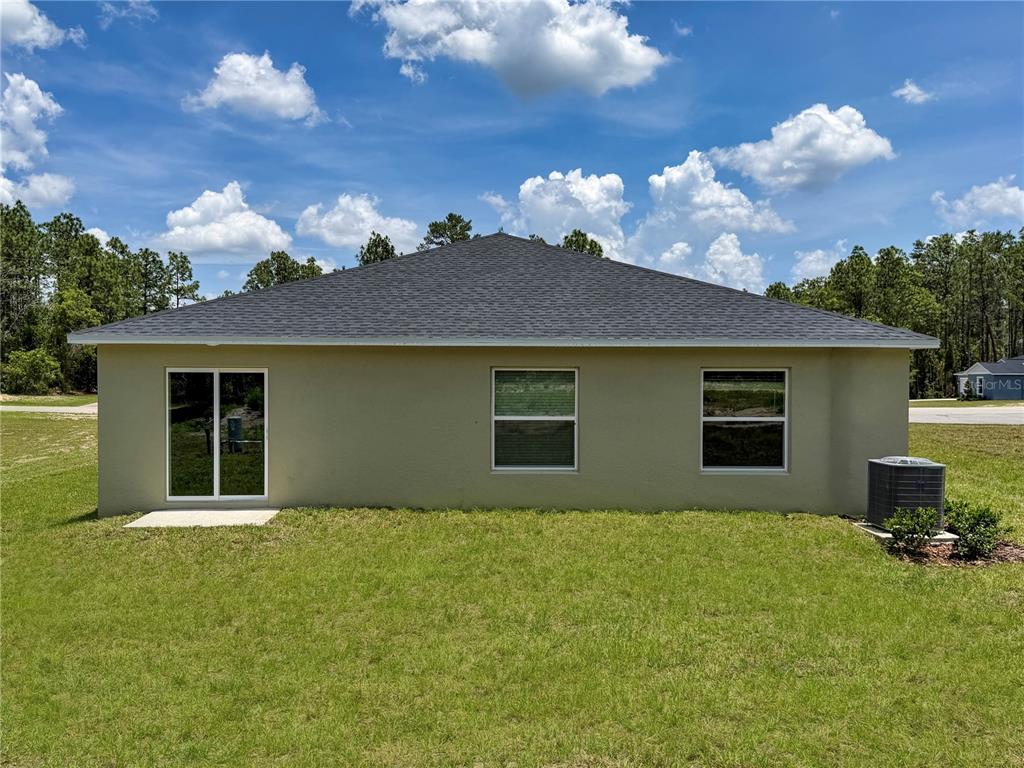 The rear exterior of a single-story house features a sliding glass door and two windows — 13121 SW 86TH COURT, OCALA, FL