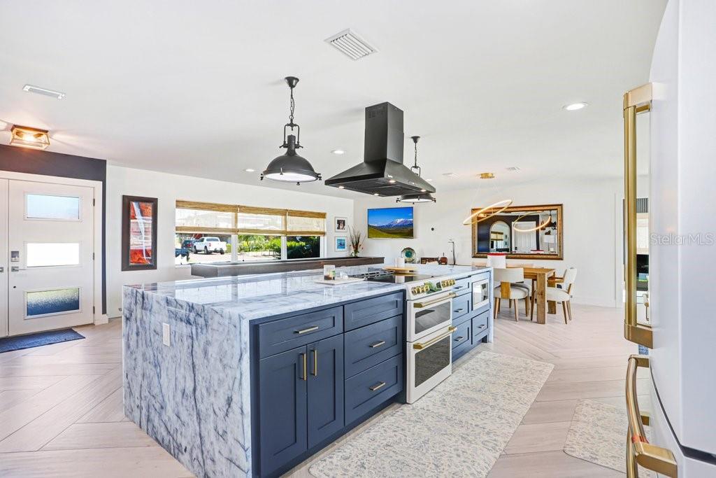 A kitchen features a large blue marble-topped island, dark blue cabinets, and a black range hood — 3926 VENETIAN WAY, TAMPA, FL