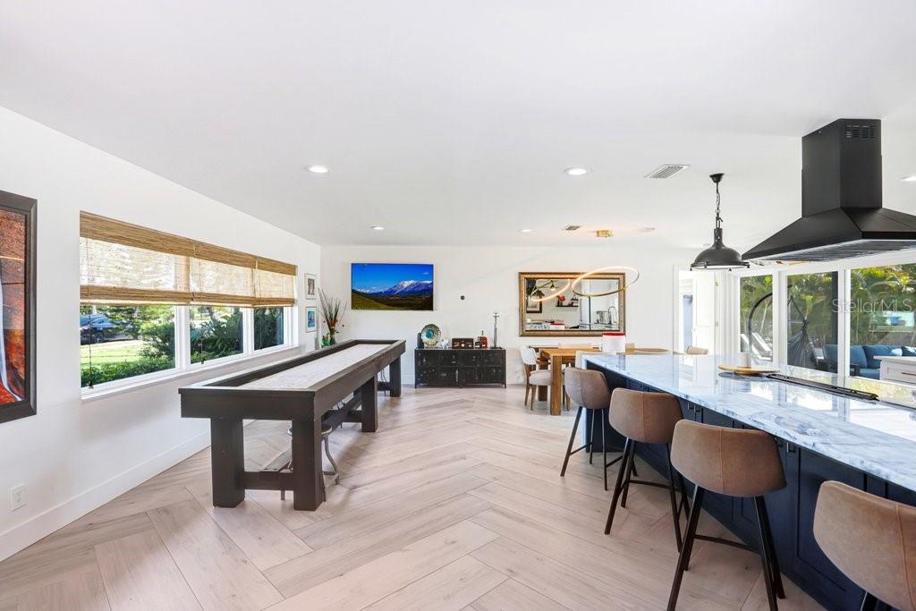 A spacious room features a shuffleboard table, kitchen island with bar stools, and herringbone flooring — 3926 VENETIAN WAY, TAMPA, FL