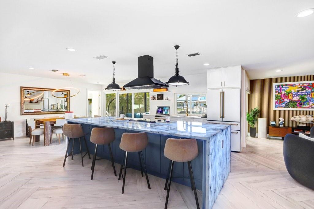 A modern kitchen features a large blue marble island, bar stools, and a black range hood — 3926 VENETIAN WAY, TAMPA, FL