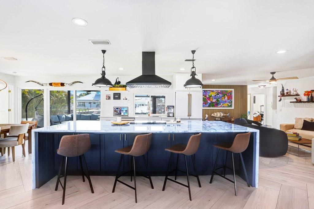A modern kitchen features a large blue marble island with four bar stools and pendant lighting — 3926 VENETIAN WAY, TAMPA, FL