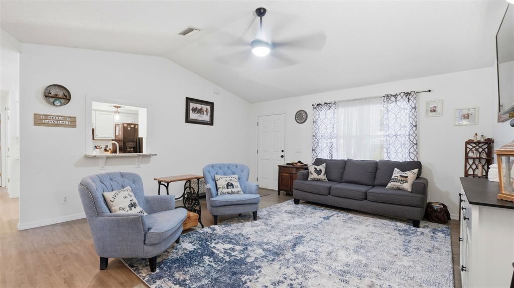 A living room features a gray sofa, two blue armchairs, and a patterned area rug — 12435 S CANNA POINT, FLORAL CITY, FL