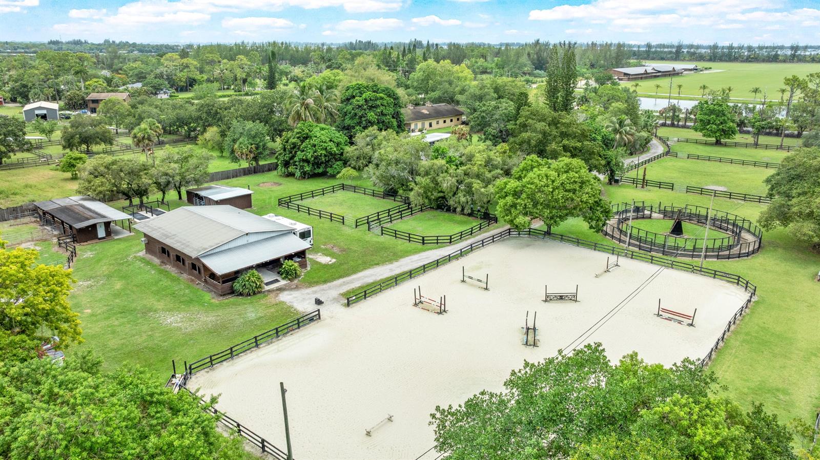 An aerial view shows a horse riding arena, stables, and fenced paddocks on a property — 14536 North Road, FL 33470, FL