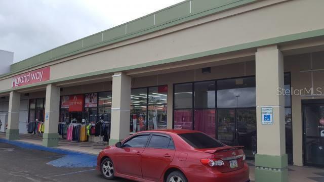 A red sedan is parked in front of a retail storefront with a Grand Way sign — 14 PR-14 KM 52.7, AIBONITO, PR