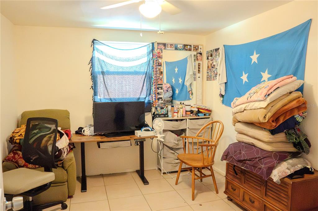 A bedroom features a desk, a chair, a stack of bedding, and blue wall flags — 636 DOGWOOD COURT, DUNEDIN, FL