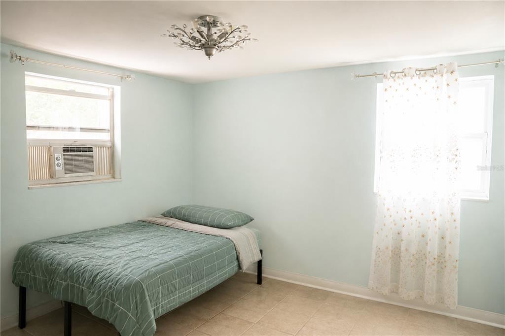 A bedroom with light blue walls, a bed, two windows, and a decorative ceiling light fixture — 636 DOGWOOD COURT, DUNEDIN, FL