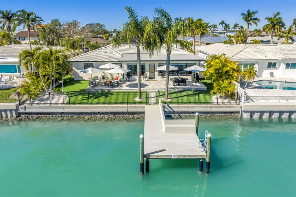 An aerial view of a waterfront house with a patio, palm trees, and a private dock — 795 CAPRI BOULEVARD, TREASURE ISLAND, FL