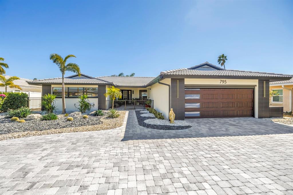 A single-story house with a paved driveway, a two-car garage, and desert-style landscaping — 795 CAPRI BOULEVARD, TREASURE ISLAND, FL