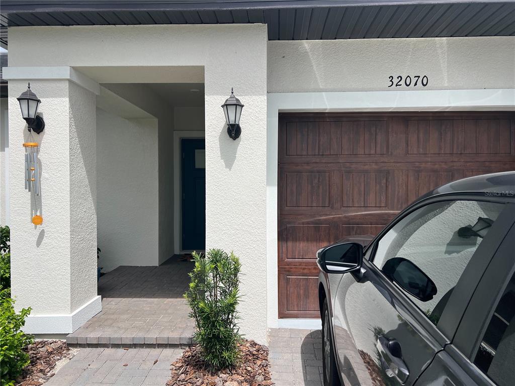 A view of a home exterior featuring a front entryway, garage, and a parked car — 32070 GRIFFIN SANDS LANE, SAN ANTONIO, FL