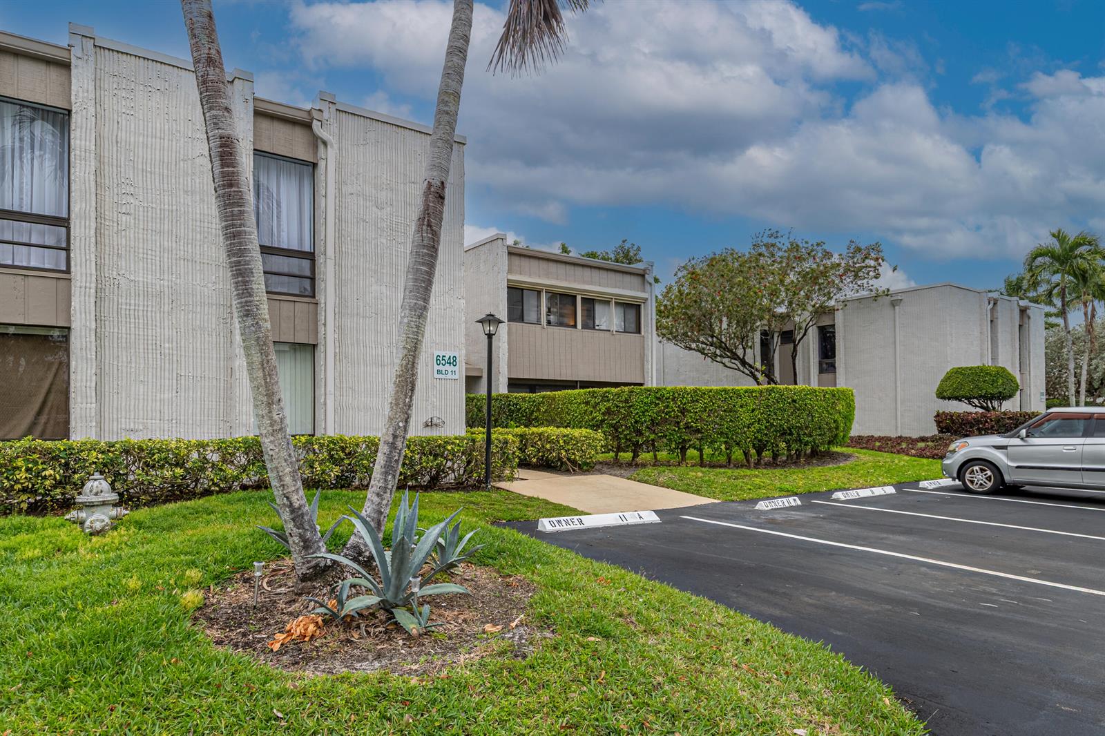 A multi-story apartment building with a parking lot, palm trees, and manicured hedges — 6548 Spring Bottom Way # 221, Boca Raton FL 33433, BOCA RATON, FL