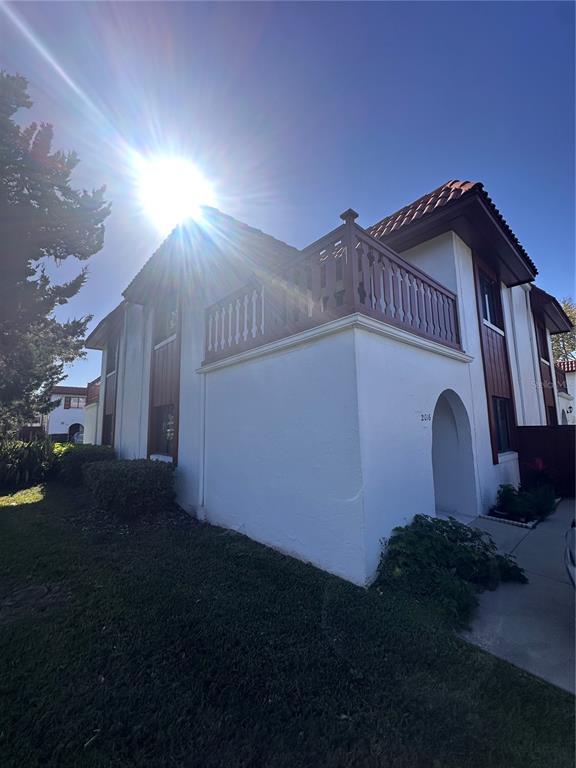 A two-story stucco building features a wooden balcony and an arched entryway under a bright sun — 2016 OAK MEADOW CIRCLE, SOUTH DAYTONA, FL