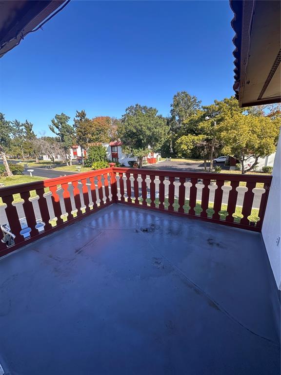 A balcony with a red wooden railing overlooks a parking lot and trees — 2016 OAK MEADOW CIRCLE, SOUTH DAYTONA, FL