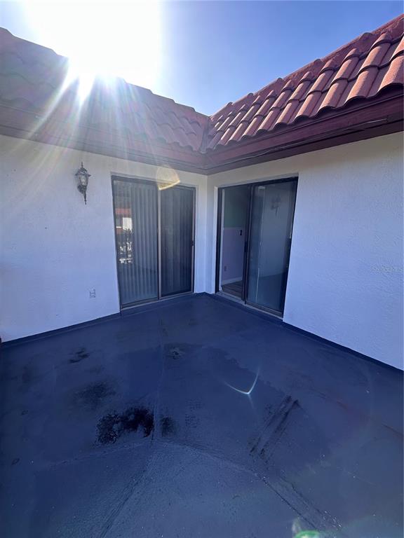 A patio with a dark painted floor and two sliding glass doors under a tiled roof — 2016 OAK MEADOW CIRCLE, SOUTH DAYTONA, FL