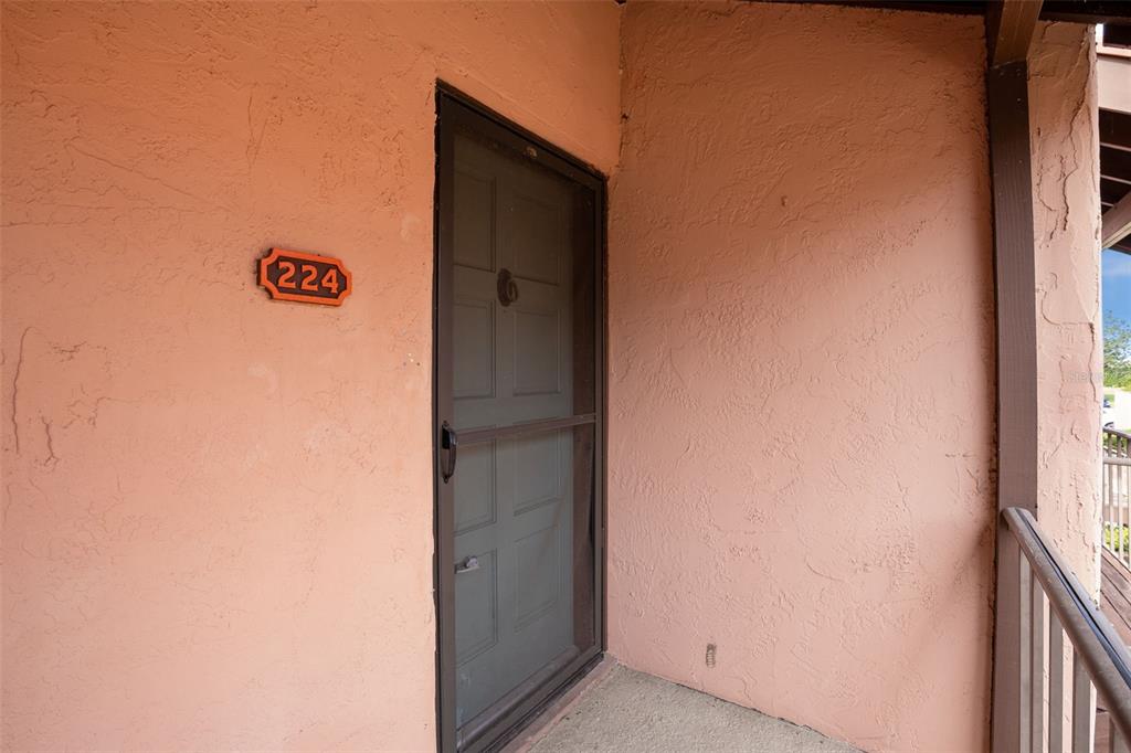 An exterior view of a peach-colored stucco wall with a door labeled 224 — 224 LA CASA UNIT 224, LAKE WALES, FL