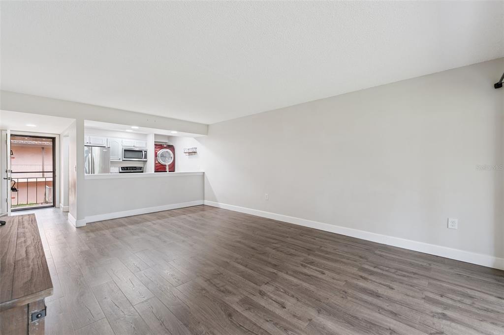 A living room with wood-look flooring, a breakfast bar, and an adjacent kitchen area — 224 LA CASA UNIT 224, LAKE WALES, FL