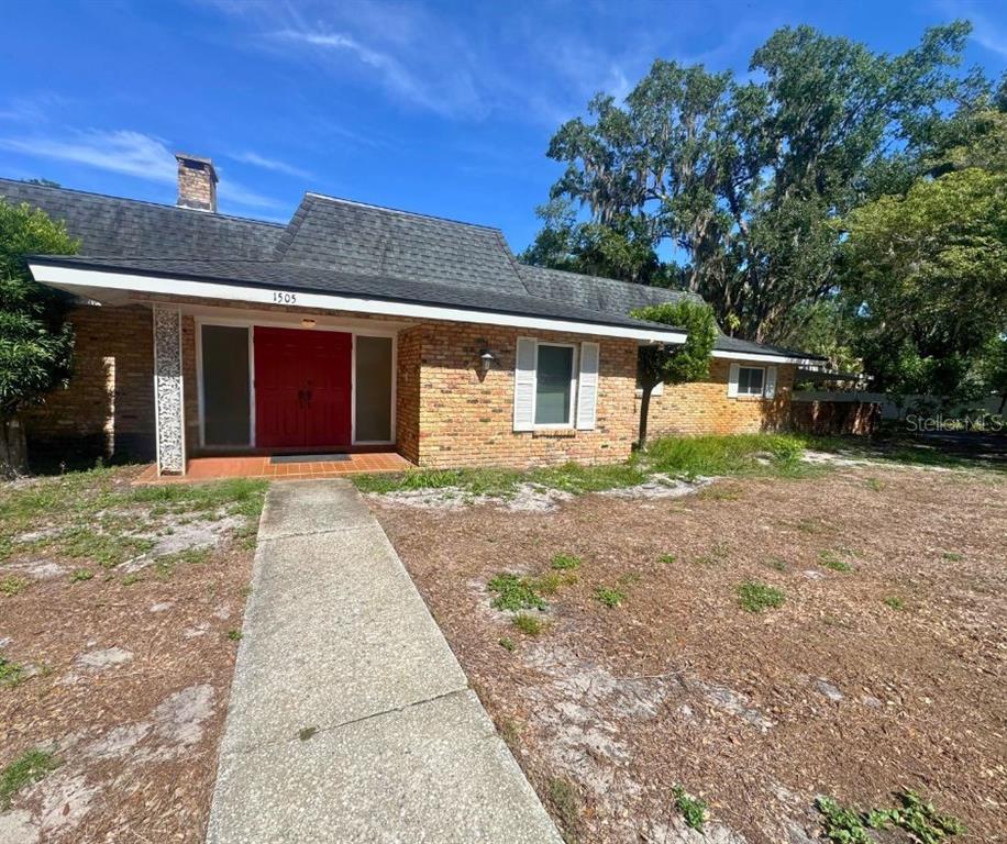 A single-story brick house with a red double front door and a shingled roof — 1505 N ARCADIA AVENUE, ARCADIA, FL