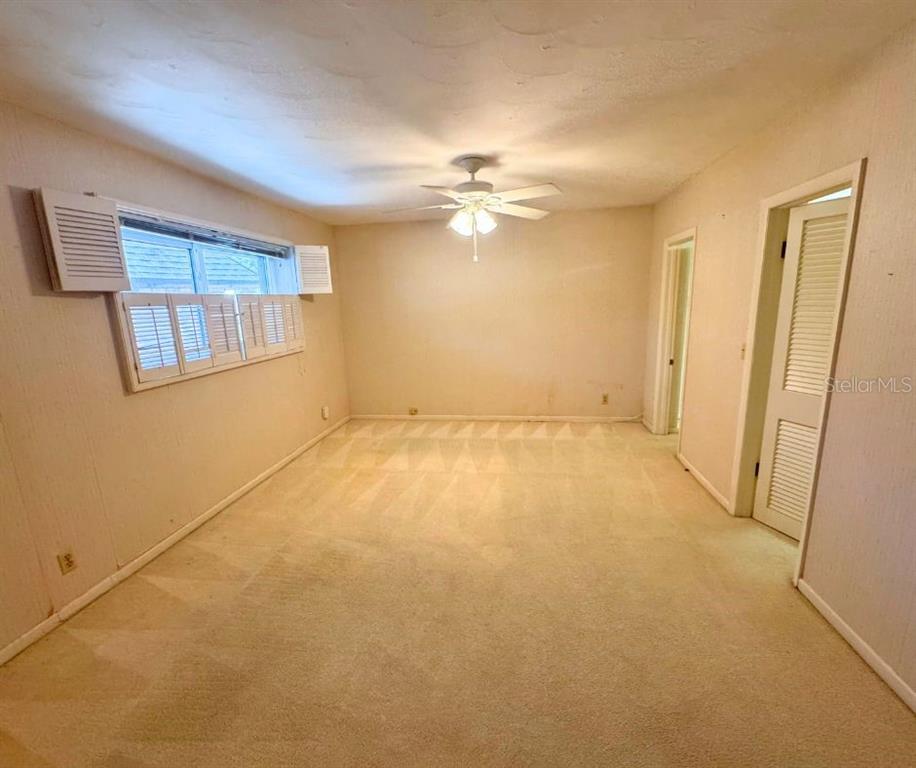 An empty bedroom features beige carpeting, white walls, a ceiling fan, and louvered window shutters — 1505 N ARCADIA AVENUE, ARCADIA, FL