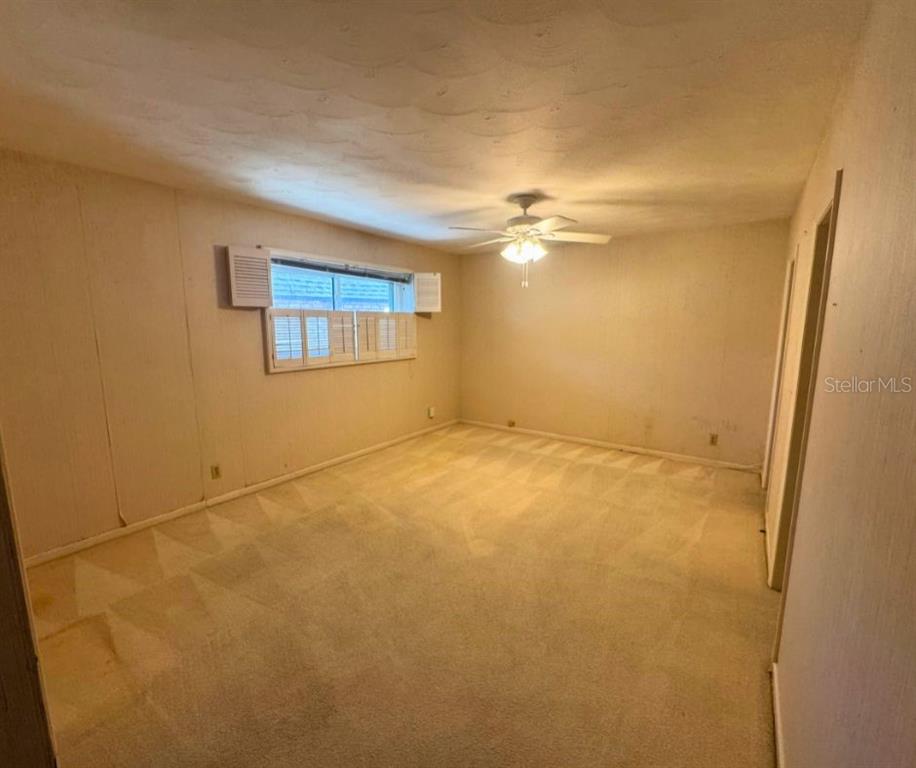 An empty bedroom features beige carpeting, off-white walls, a ceiling fan, and window shutters — 1505 N ARCADIA AVENUE, ARCADIA, FL