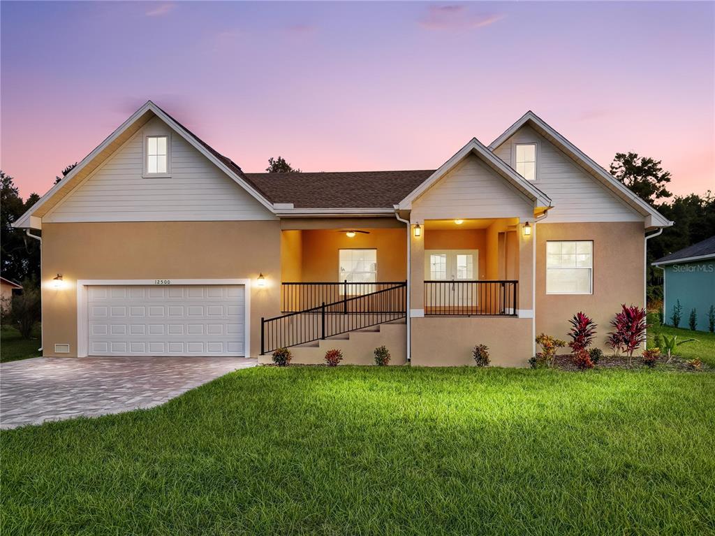 A single-story house with a tan stucco exterior, a two-car garage, and a front ramp — 12500 GREEN OAK LANE, DADE CITY, FL