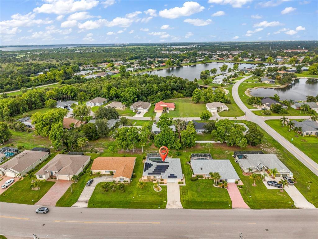 An aerial view shows a suburban house with a solar-paneled roof and pool enclosure — 2399 RIO DE JANEIRO AVENUE, PUNTA GORDA, FL