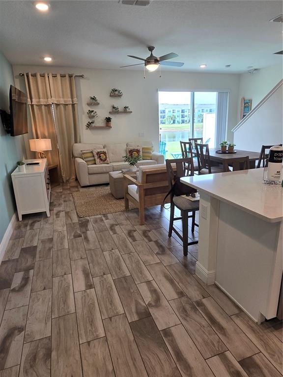 An open-concept living and dining area features wood-look tile flooring and a sliding glass door — 3145 CARIBBEAN SOUL DRIVE, KISSIMMEE, FL