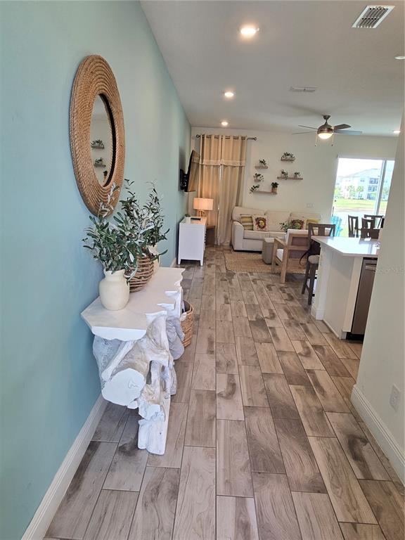 A view of a living room and kitchen area featuring light wood-look tile flooring — 3145 CARIBBEAN SOUL DRIVE, KISSIMMEE, FL