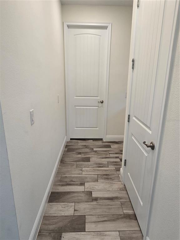 A hallway with white doors, light-colored walls, and wood-look tile flooring — 3145 CARIBBEAN SOUL DRIVE, KISSIMMEE, FL