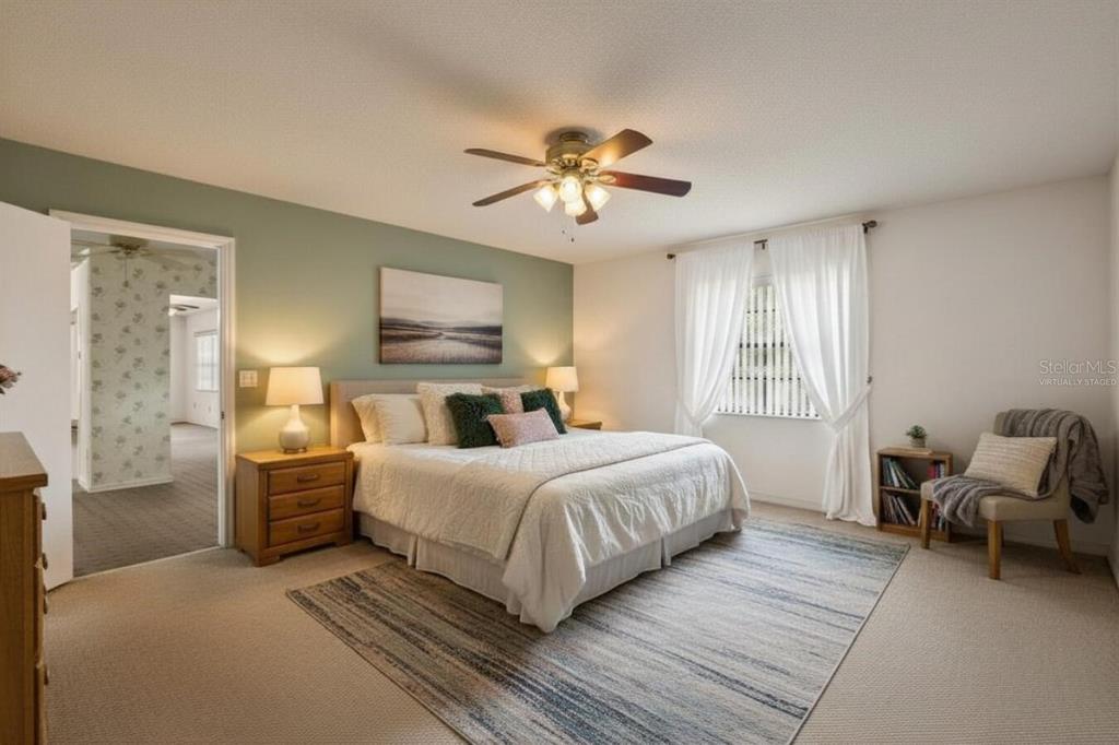 A bedroom features a king-sized bed, a sage green accent wall, and a ceiling fan — 914 SUN KEY COURT, SUN CITY CENTER, FL