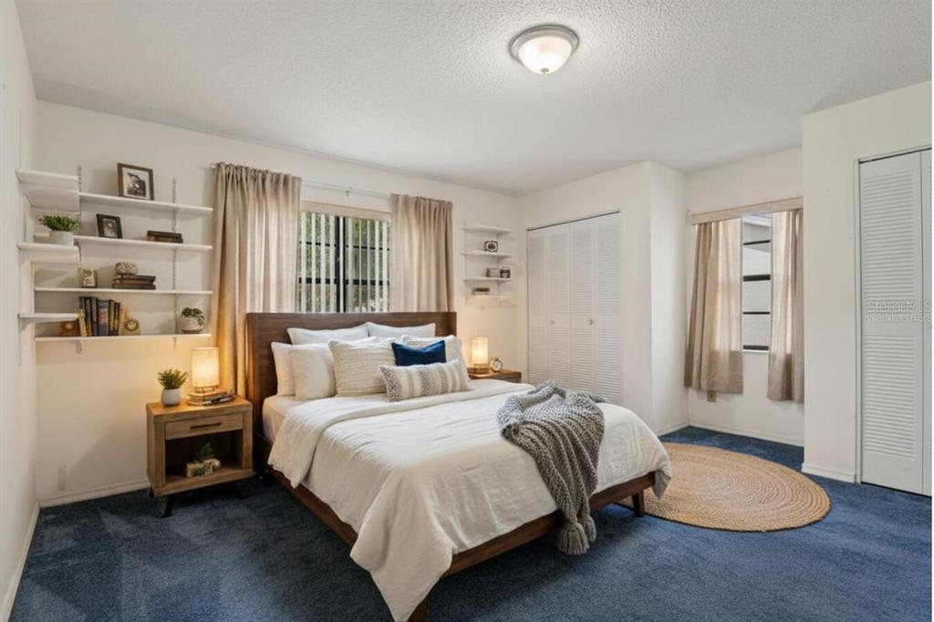 A bedroom with blue carpeting, a wooden bed frame, white walls, and built-in shelving — 914 SUN KEY COURT, SUN CITY CENTER, FL