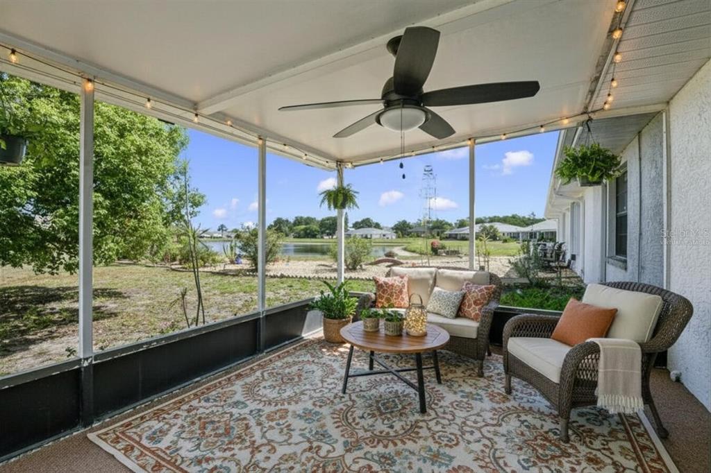 A spacious, carpeted living room features white walls, a ceiling fan, and a dining chandelier — 914 SUN KEY COURT, SUN CITY CENTER, FL