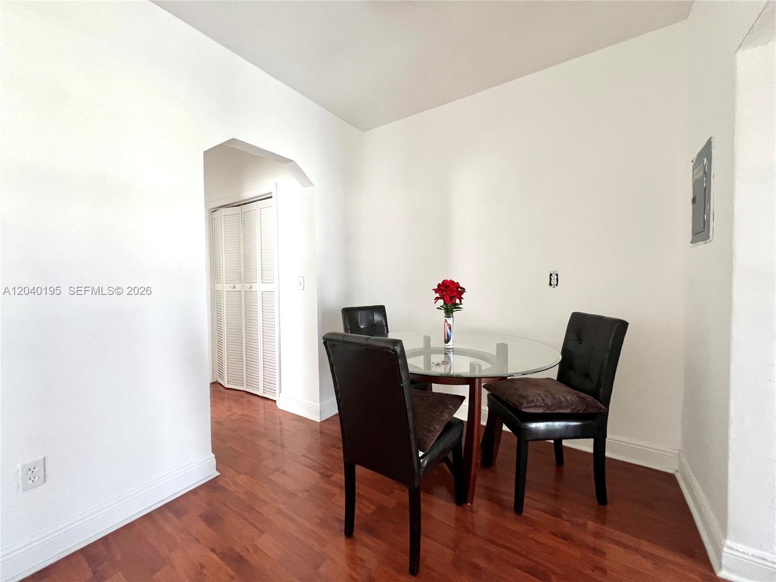 A dining area features a glass-topped table, three black chairs, and hardwood flooring — 450 77th St # 6, Miami Beach FL 33141, MIAMI BEACH, FL