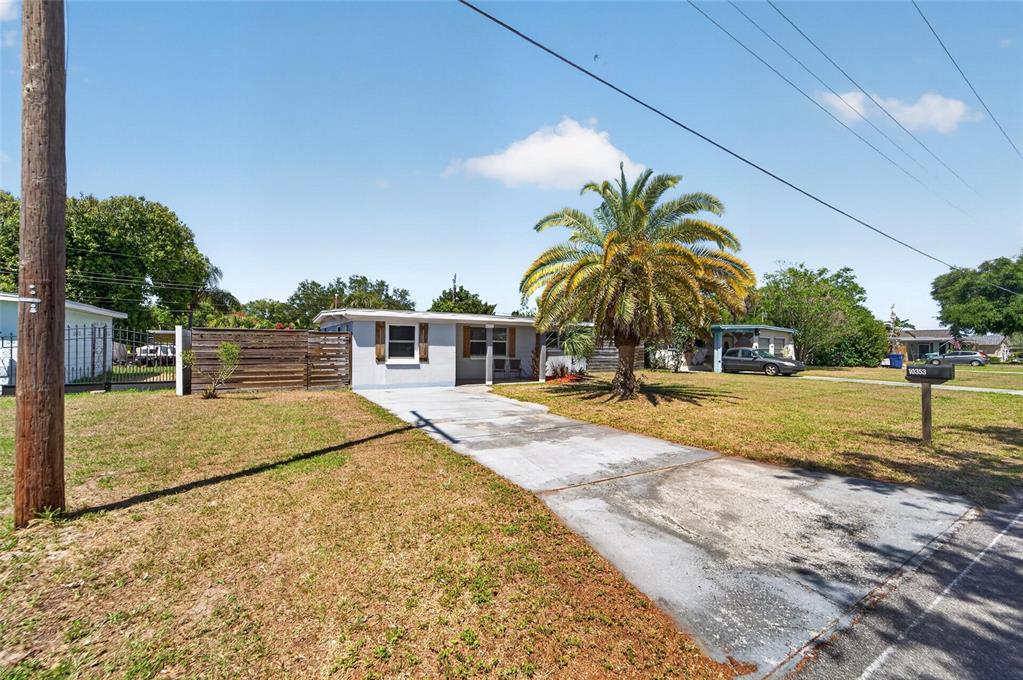 A single-story house with a concrete driveway, a palm tree, and a wooden fence — 10353 110TH AVENUE, LARGO, FL