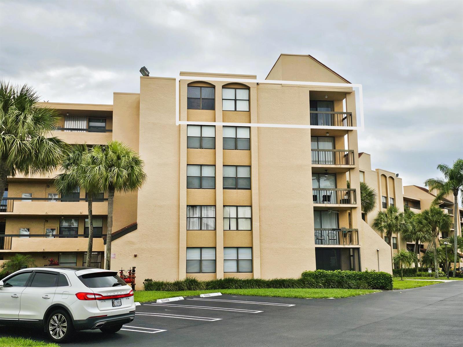 A multi-story tan stucco apartment building with a white outline highlighting the top floor unit — 2255 Lindell Boulevard # 4511, Delray Beach FL 33444, DELRAY BEACH, FL