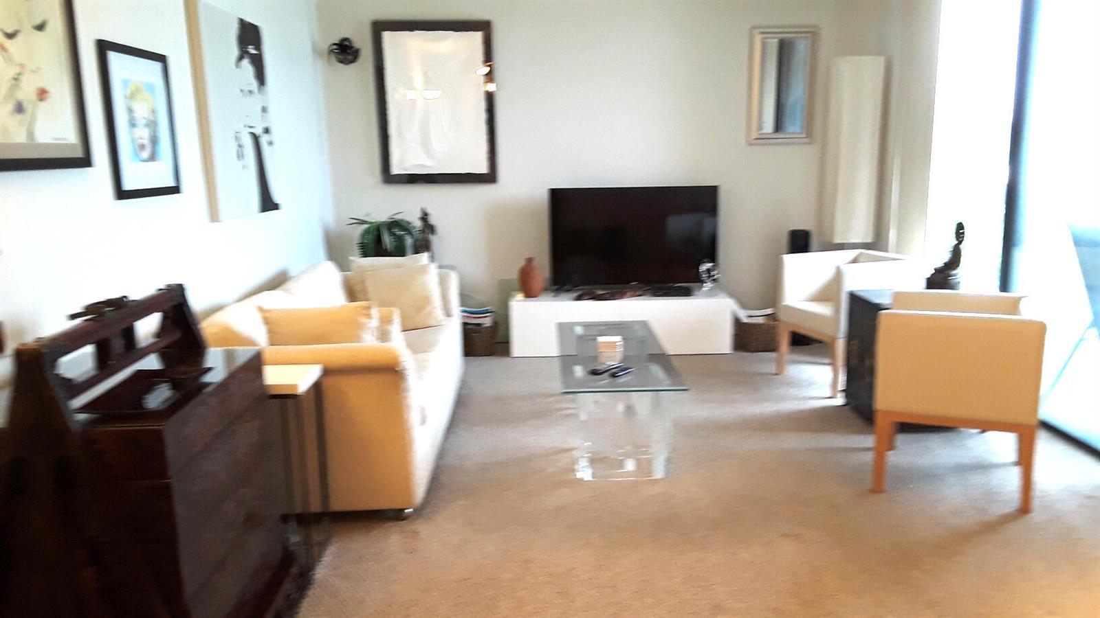 A living room features a beige sofa, two armchairs, a glass coffee table, and television — 2255 Lindell Boulevard # 4511, Delray Beach FL 33444, DELRAY BEACH, FL