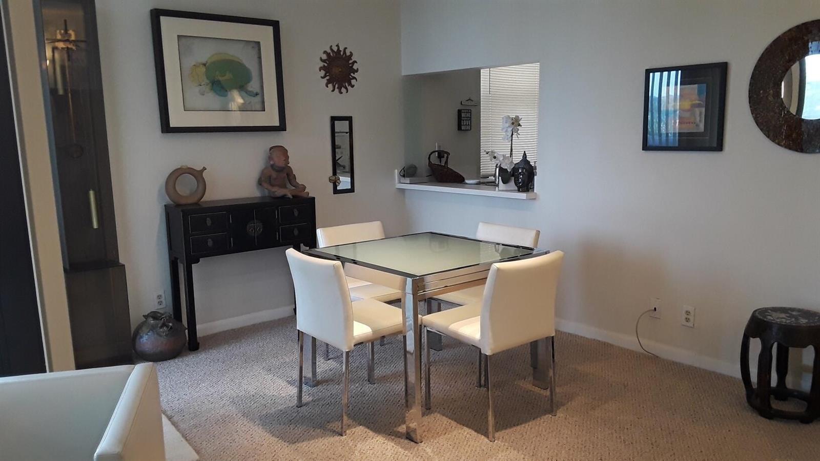 A dining area features a glass-topped table with four white chairs and a black console — 2255 Lindell Boulevard # 4511, Delray Beach FL 33444, DELRAY BEACH, FL