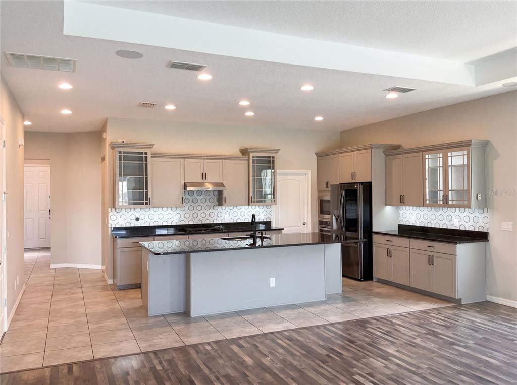 A kitchen features gray cabinetry, a large island with a dark countertop, and tiled flooring — 2185 ANTILLES CLUB DRIVE, KISSIMMEE, FL