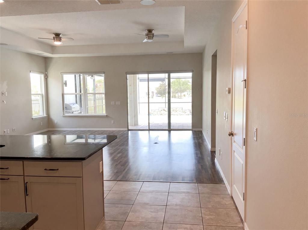 A kitchen island overlooks a living area with tile flooring, wood-look floors, and sliding doors — 2185 ANTILLES CLUB DRIVE, KISSIMMEE, FL