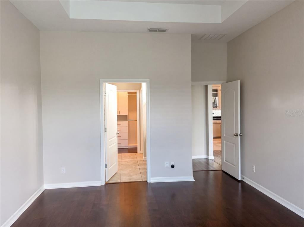 A room with dark wood floors, a tray ceiling, and two open doorways — 2185 ANTILLES CLUB DRIVE, KISSIMMEE, FL