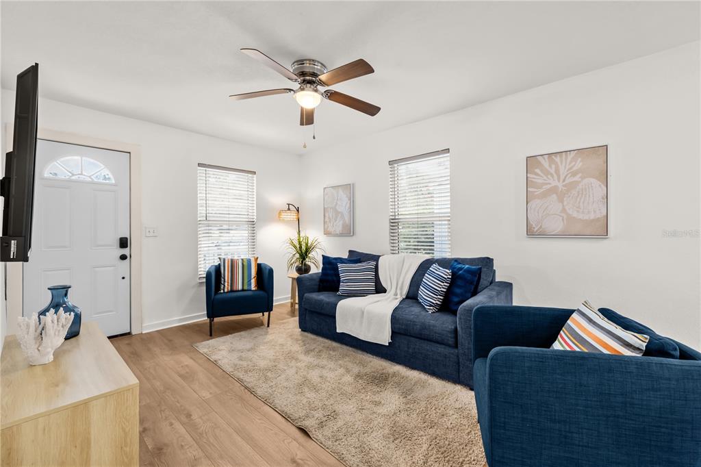 A living room features a blue sofa, two matching armchairs, and light wood flooring — 3906 N OLA AVENUE, TAMPA, FL