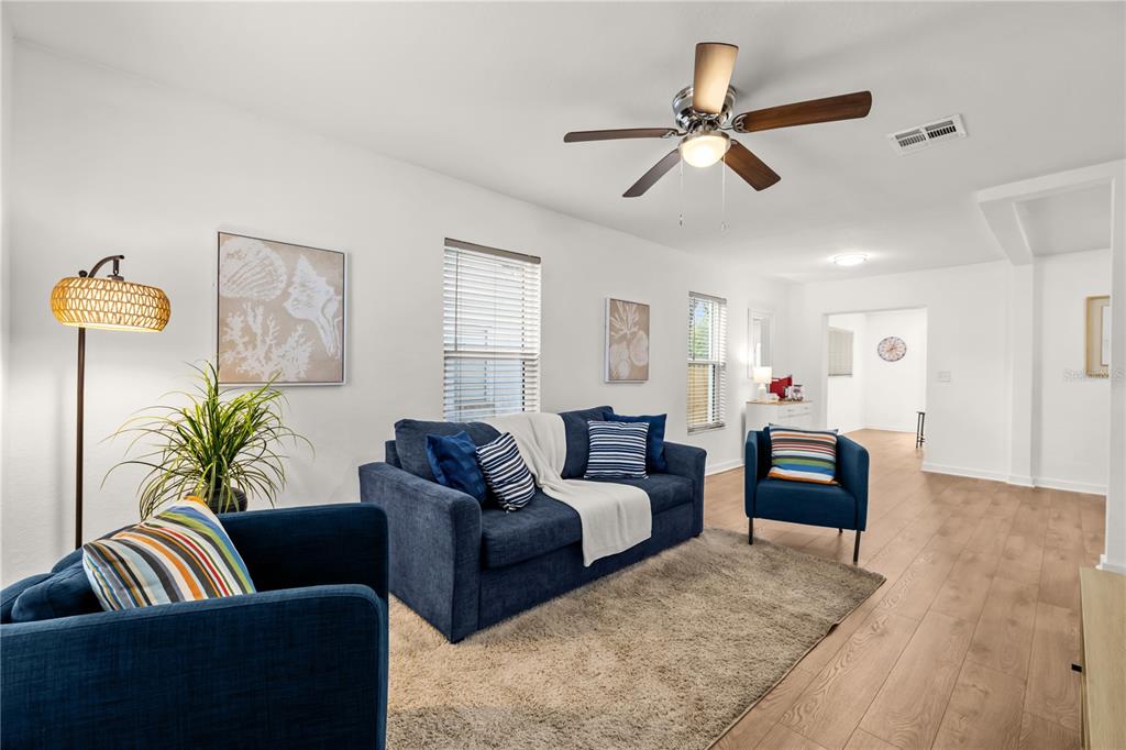 A living room features a blue sofa, two armchairs, a ceiling fan, and wood flooring — 3906 N OLA AVENUE, TAMPA, FL