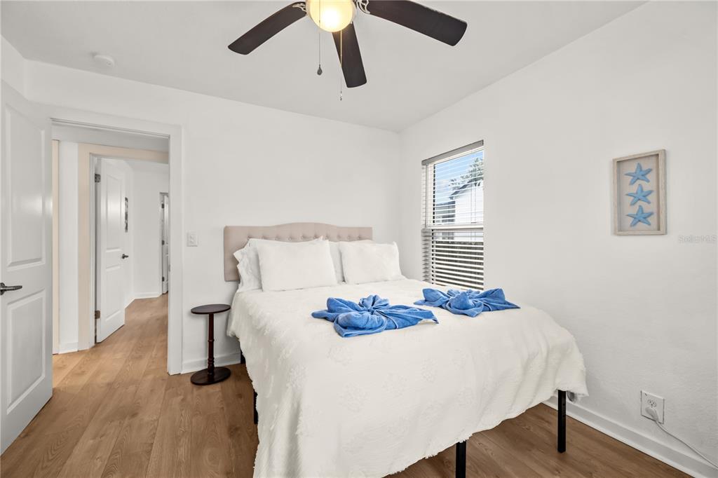 A bedroom features a bed with white bedding, blue towels, and a ceiling fan — 3906 N OLA AVENUE, TAMPA, FL
