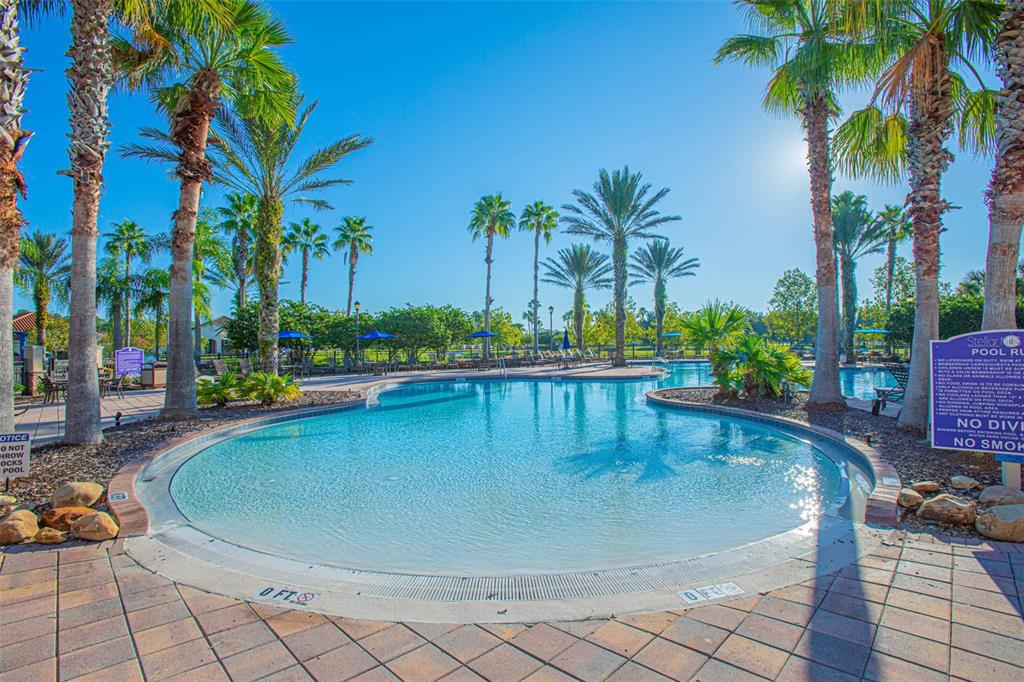 A swimming pool with a zero-entry edge is surrounded by palm trees and lounge chairs — 3524 SHOREWOOD DRIVE, KISSIMMEE, FL