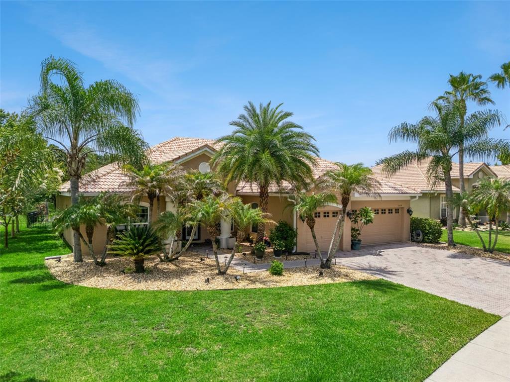 A single-story tan house with a tile roof, a paved driveway, and several palm trees — 3524 SHOREWOOD DRIVE, KISSIMMEE, FL