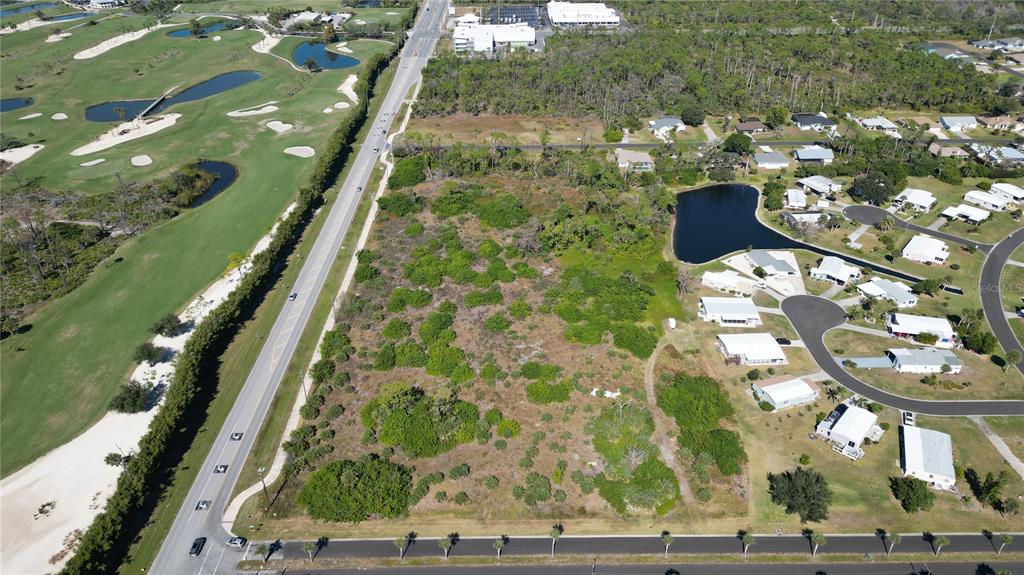 An aerial view shows a vacant, wooded lot situated between a road and a residential neighborhood — 6691 PLACIDA ROAD, ENGLEWOOD, FL