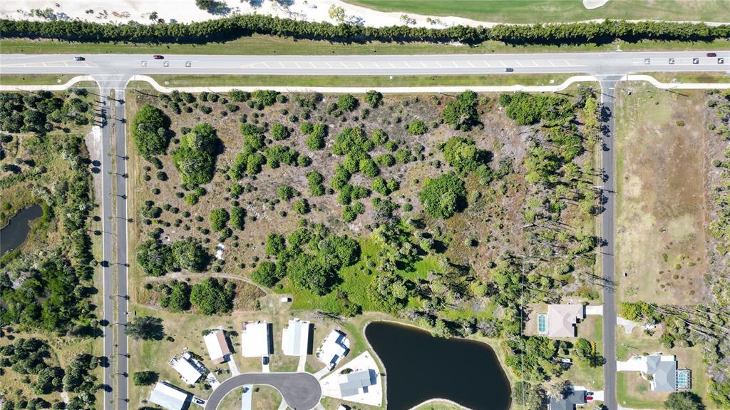 An aerial view shows a vacant, wooded lot bordered by roads and residential houses — 6691 PLACIDA ROAD, ENGLEWOOD, FL
