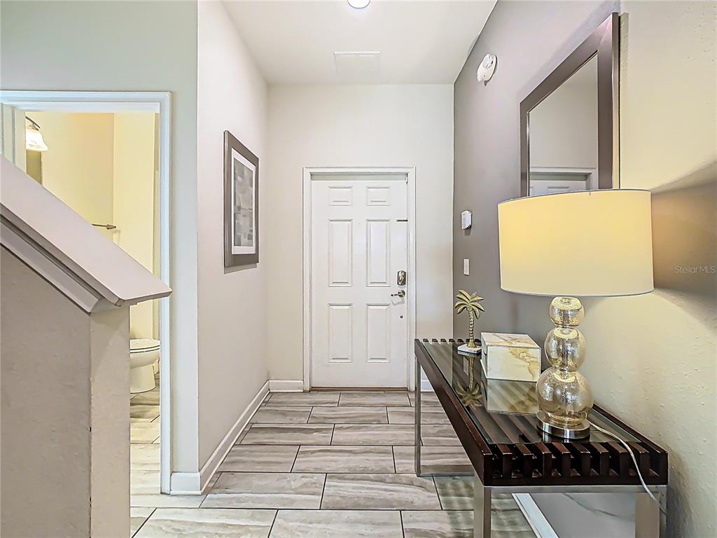 An entryway features a white front door, tiled flooring, a console table, and a lamp — 1579 MOON VALLEY DR, DAVENPORT, FL