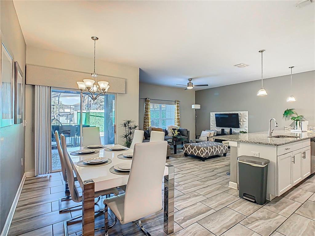 A dining area with a white table and chairs sits adjacent to a modern kitchen — 1579 MOON VALLEY DR, DAVENPORT, FL